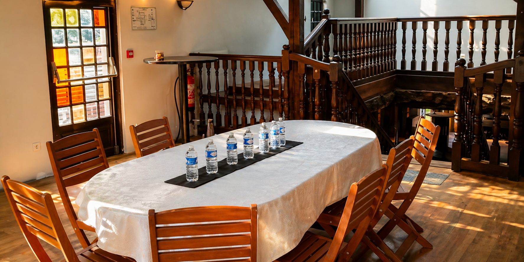 Salle Mezzanine dressée pour une réunion, table ovale et escalier en bois